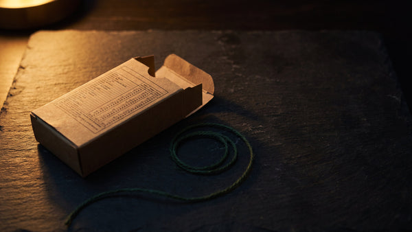 An open kraft carton on dark slate with its printed ingredient panel facing up under warm lamp light